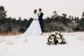 Wedding bouquet lying on snowy ground with couple in background Royalty Free Stock Photo